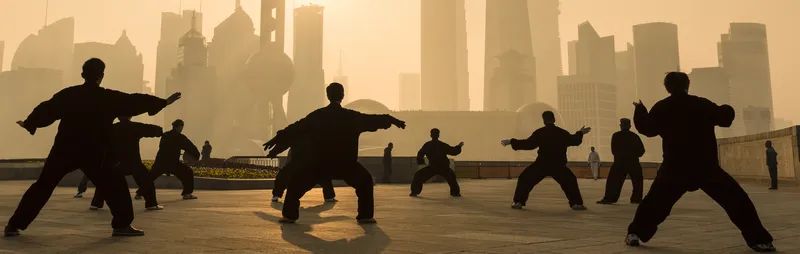 Locals exercise performing martial arts on Shanghai's riverfront as the sun rises. 